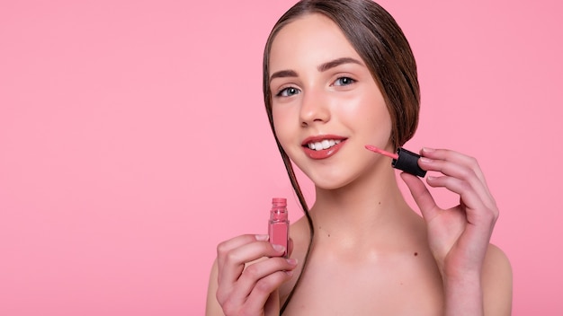 Beauty, skin care and people concept - Beautiful young woman with lipstick over abstract pink background. 16:9 panoramic format.