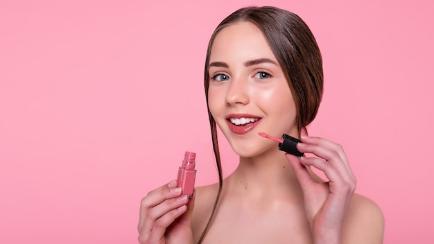 Beauty, skin care and people concept - Beautiful young woman with lipstick over abstract pink background. 16:9 panoramic format.