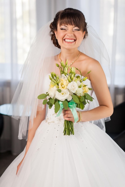 Beauty smiling bride with bouquet in the room