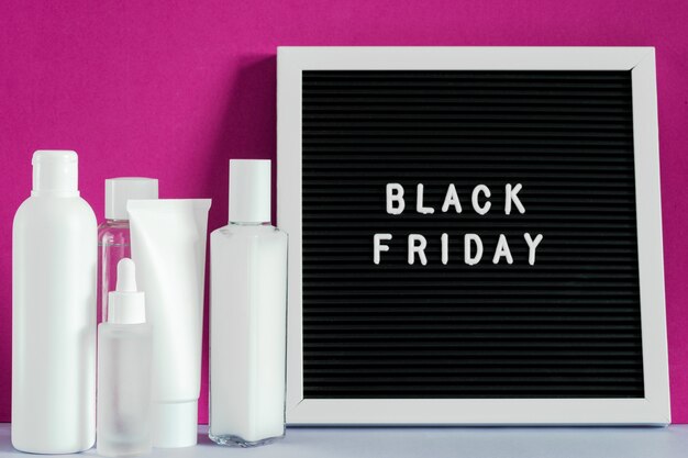 Beauty spa-behandeling huidverzorging cosmetische crème gezichtsbuis container productverpakking op paarse achtergrond, black friday op letterbord. cosmetische korting concept