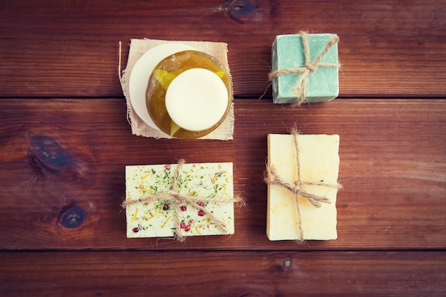 beauty, spa, body care, bath and natural cosmetics concept - close up of handmade soap bars on wooden table