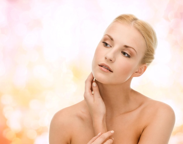 beauty and spa concept - face of beautiful woman touching her face skin