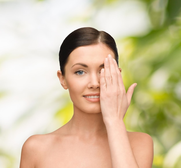 beauty, spa and health concept - smiling young woman covering half of face with hand