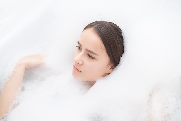 Beauty spa personal care Young woman relaxes in the bath with foam