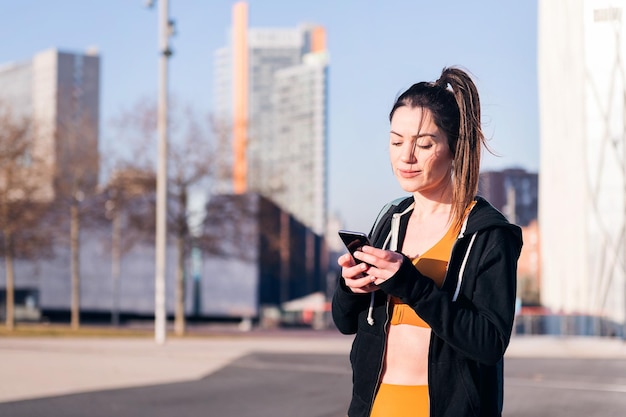 Beauty sports woman using a mobile in the city