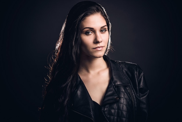 Beauty in style. Beautiful young woman in leather jacket looking at camera while standing 