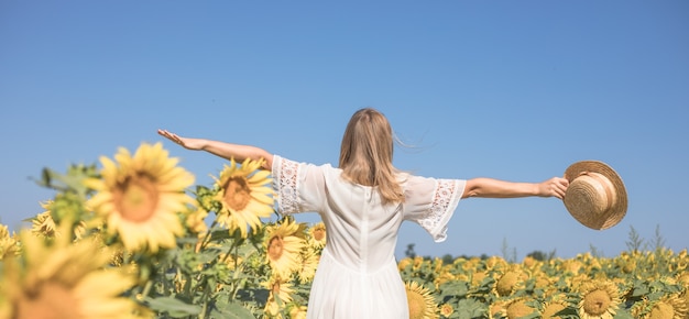 Beauty sunlit woman on yellow sunflower field Freedom and happiness concept Happy girl outdoors