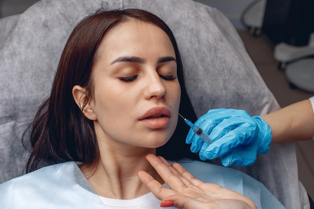 Beauty therapy in a beauty salon. Injections in the lips with collagen. The cosmetologist gives injections to the girl.