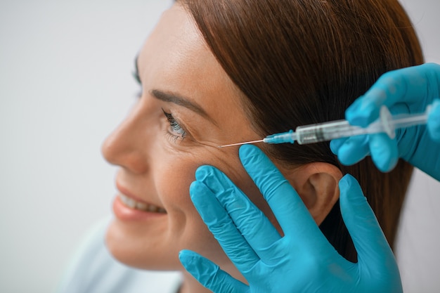 Beauty treatment. A dark-haired mid aged woman having a beaty injections procedure