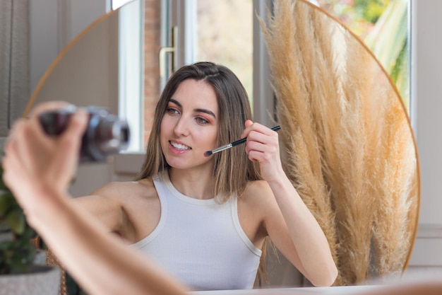 Beauty vlogger influencer woman filming makeup routine tutorial\
on camera