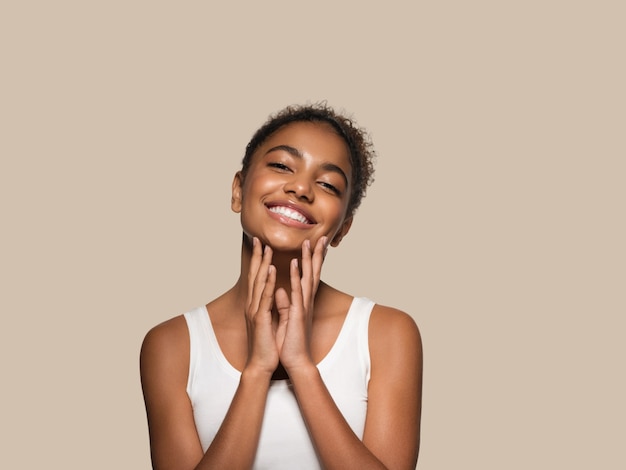 Beauty woman black skin face smiling model touching her face. Color background. Brown