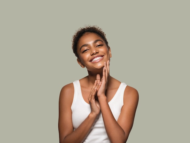 Beauty woman black skin face smiling model touching her face. Color background. Green