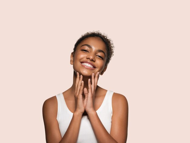 Beauty woman black skin face smiling model touching her face. Color background. Pink