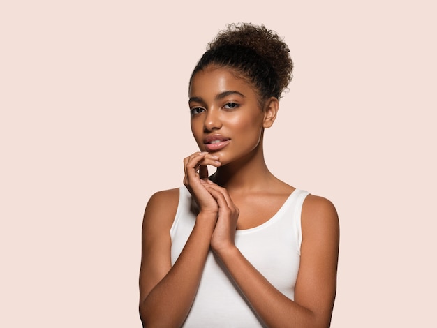 Beauty woman black skin face smiling model touching her face. Color background. Pink