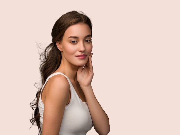 Beauty woman face healthy skin care female beautiful woman Touching her face. Color pink background