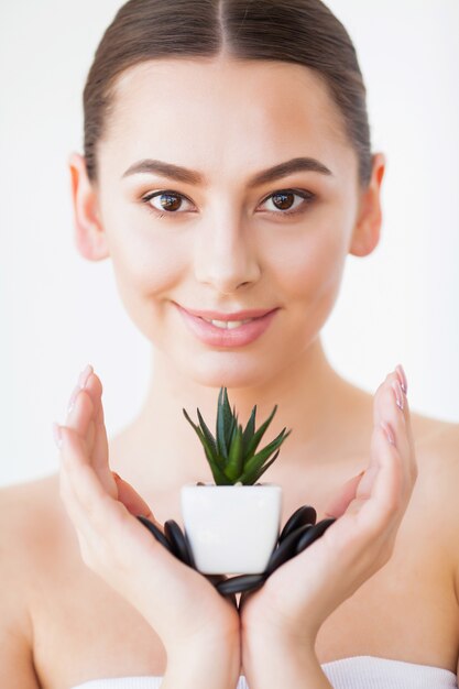 健康な皮膚と緑の植物の美容女性顔