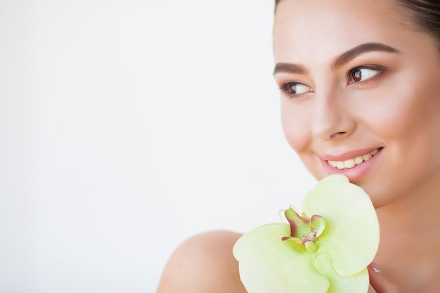 健康な皮膚と緑の植物の美容女性顔