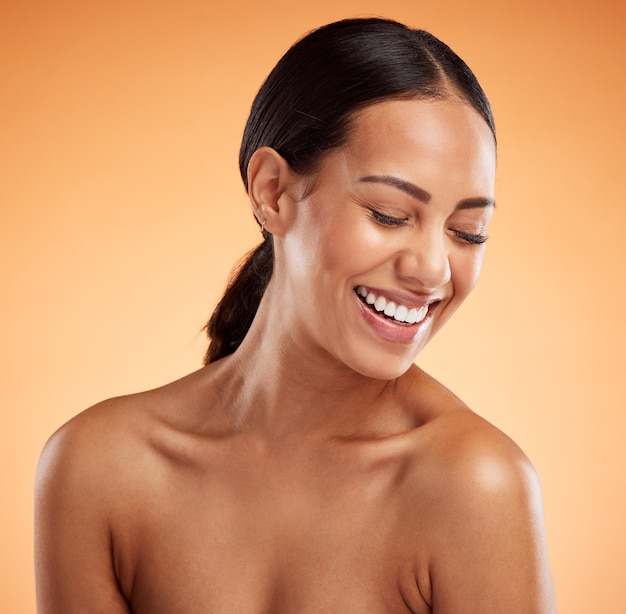 Beauty woman and laughing wellness natural skincare and makeup aesthetic cosmetics and glowing skin on orange studio background Smile happy and funny female model headshot and body dermatology