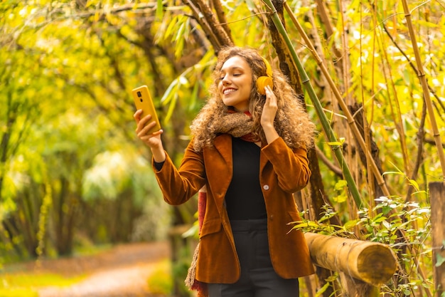 Beauty woman listening to music with headphones in a park in autumn