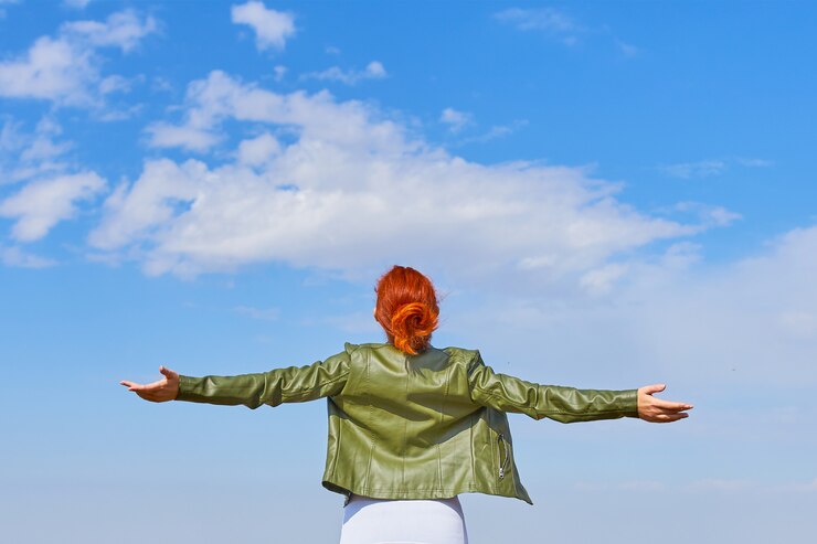 Beauty woman outdoors enjoying nature. A tourist girl on a mountain and looks at the sunrise.