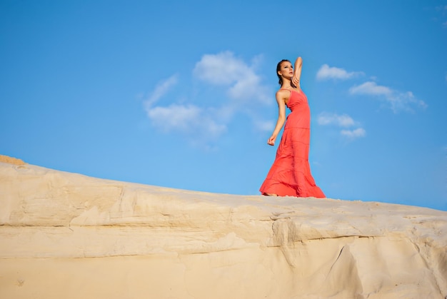 Beauty woman in red dress on the desert