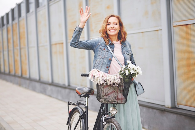 Donna di bellezza con la bici che saluta per qualcuno