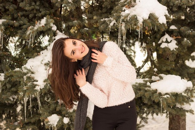 Красота женщины без шляпы в зимнем парке возле дерева со снегом