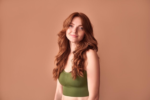 The beauty of a woman young woman in underwear with red hair on a beige background