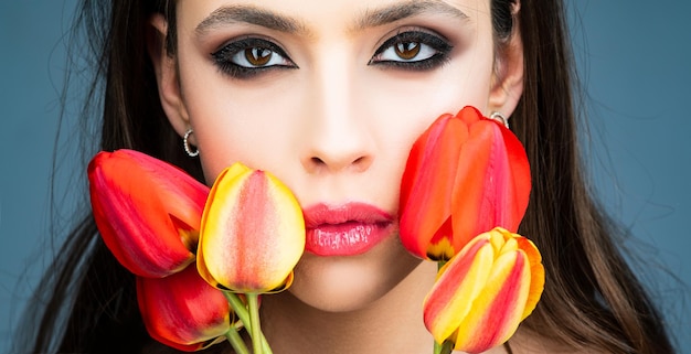 Beauty women face close up. Beautiful woman with tulips flowers.