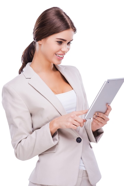 직장에서 아름다움입니다. 흰색 배경에 서서 디지털 태블릿을 들고 있는 자신감 있는 젊은 여성의 측면