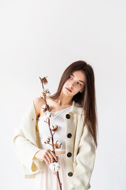 Beauty and youth Concept. Beautiful woman in cozy clothes holding branch of cotton flowers