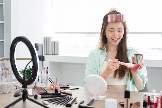 Beautyblogger-concept Jonge vrouw gebruikt penseel om blush aan te brengen tijdens het beoordelen van het product op Vlog