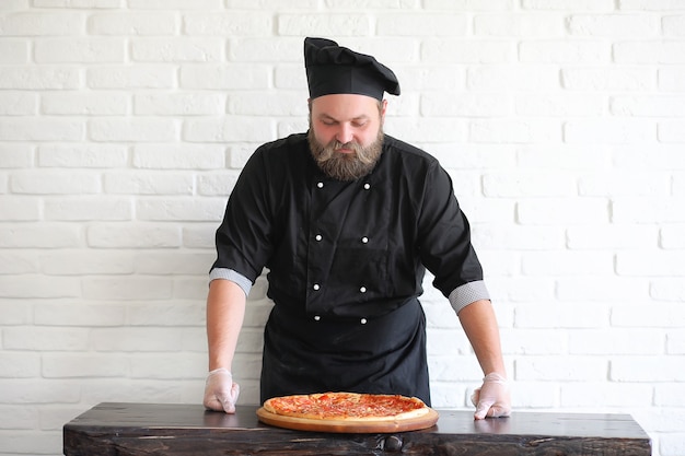 Bebaarde chef-kok bereidt maaltijden aan tafel in de keuken