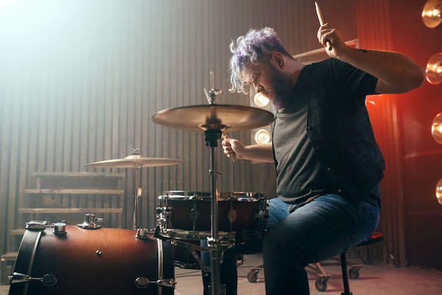 Bebaarde drummer met kleurrijke haren op het podium