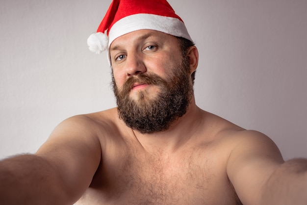 Bebaarde halfnaakte kerstman die een selfie maakt