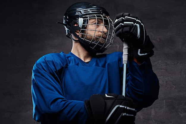 Bebaarde hockeyspeler van middelbare leeftijd die volledige sportuitrusting draagt met een hockeystick