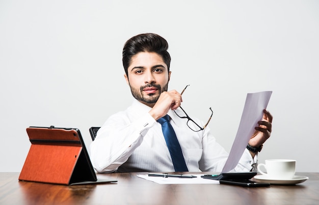 Bebaarde indiase zakenman boekhouding zittend aan een bureautafel in kantoor