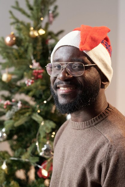 Bebaarde jonge man in kerstmuts en bril
