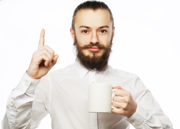 Bebaarde jonge man koffie drinken en duim opdagen.