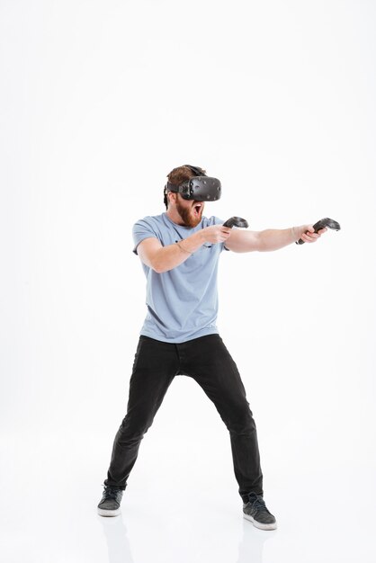 Bebaarde jonge man schreeuwen met virtual reality-apparaat staande.