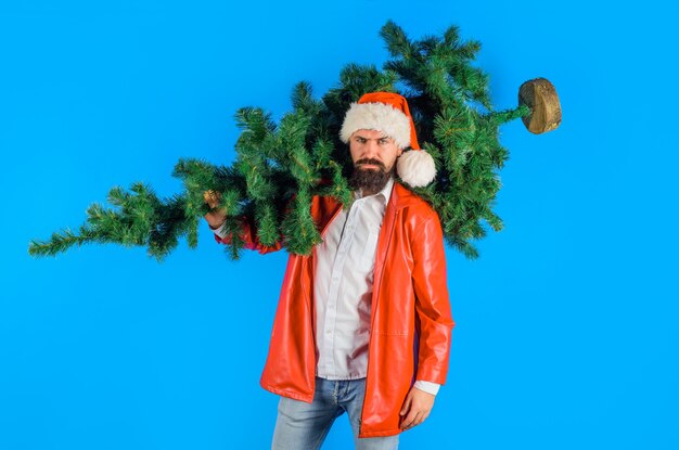 Bebaarde kerstman draagt kerstboom op schouders kerstmisnieuwjaar man in rood jasje draagt dennen