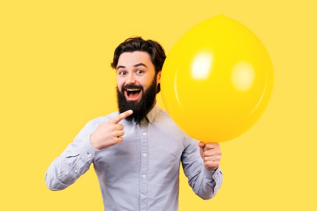 Bebaarde lachende man wijzend op een gele ballon