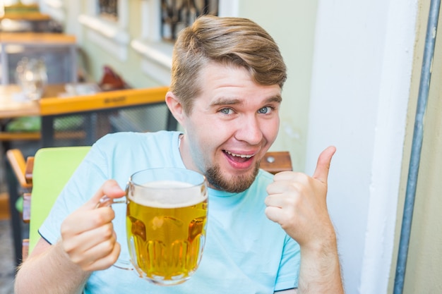 Foto bebaarde man bier drinken uit een bierpul. toont het teken duimen omhoog.