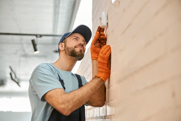 Bebaarde man die beveiligingscamera aan de muur controleert