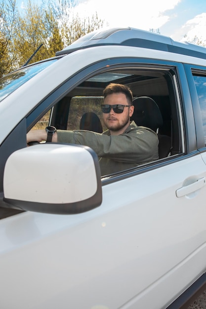 Bebaarde man die de auto kopieerruimte zomertijd bestuurt