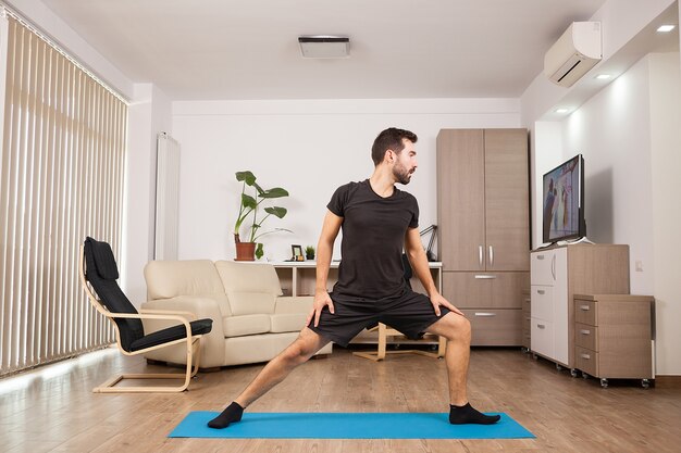 Bebaarde man doet Warrior II yoga poseren en zijn spieren strekken. Fysieke gezondheid.