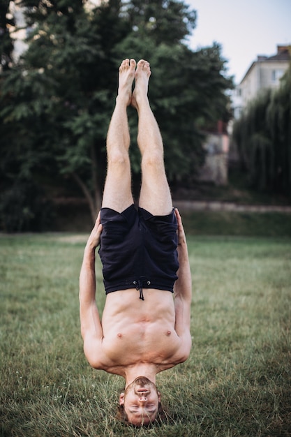 Bebaarde man doet yoga in het groene park