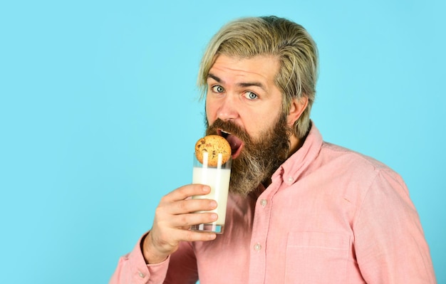 bebaarde man drinkt nuttige melk met gebak. Het concept van gezond eten. Biologische boerderijproducten voor ontbijt of lunch. melk en koekjes. gelukkige boer eet koekjesdessert.