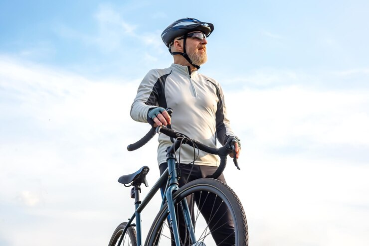 Foto bebaarde man fietser staat met een fiets tegen de blauwe lucht fietsen en gezondheid hobby's