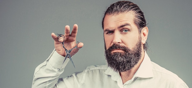 Bebaarde man geïsoleerd op grijze achtergrond Mans kapsel in de kapperszaak Kappersschaar kapperszaak Kappersschaar